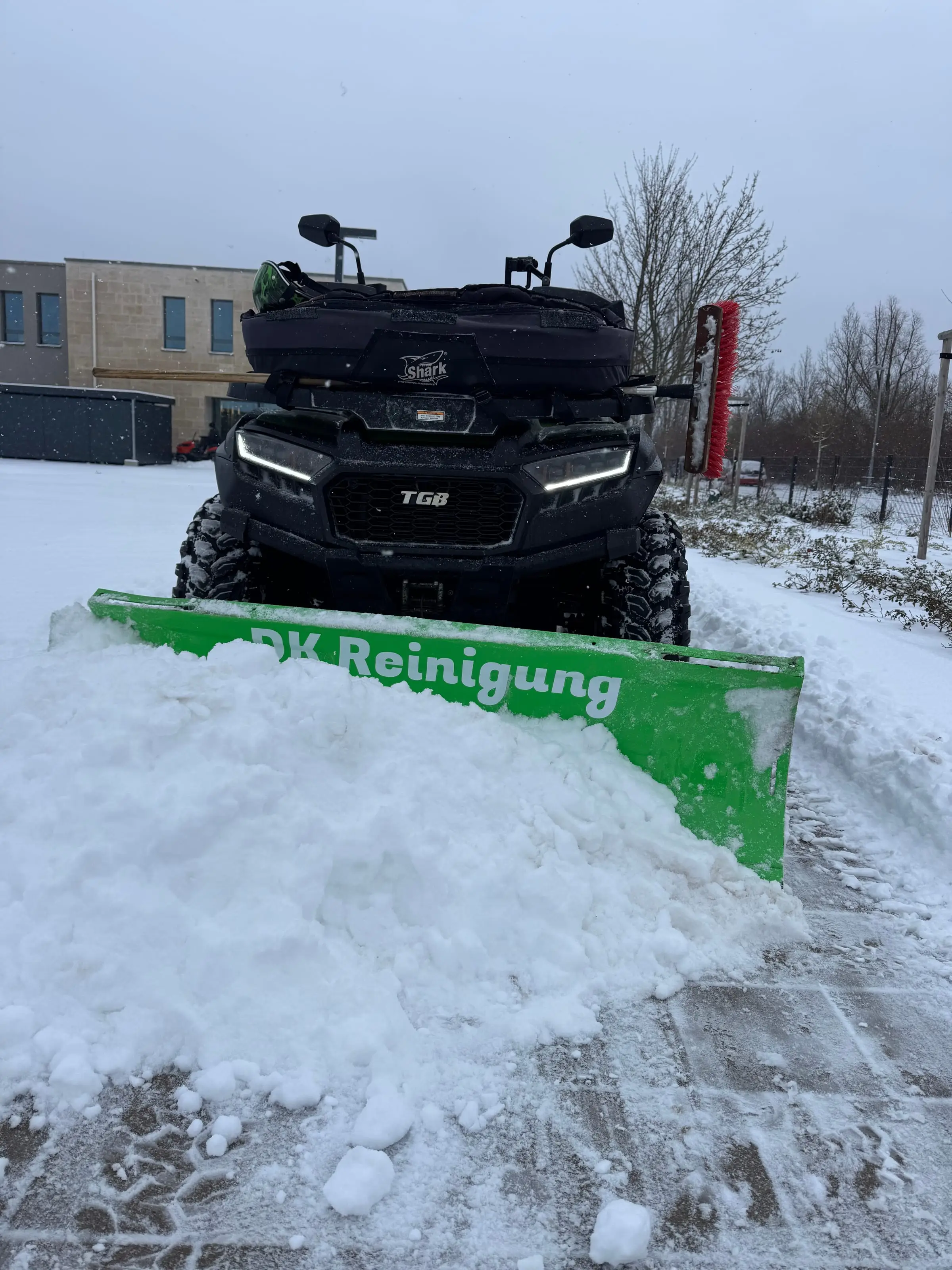 Quad von DK-Gebäudereinigung mit grünem Schneeschild beim Schneeräumen im Winterdienst-Einsatz